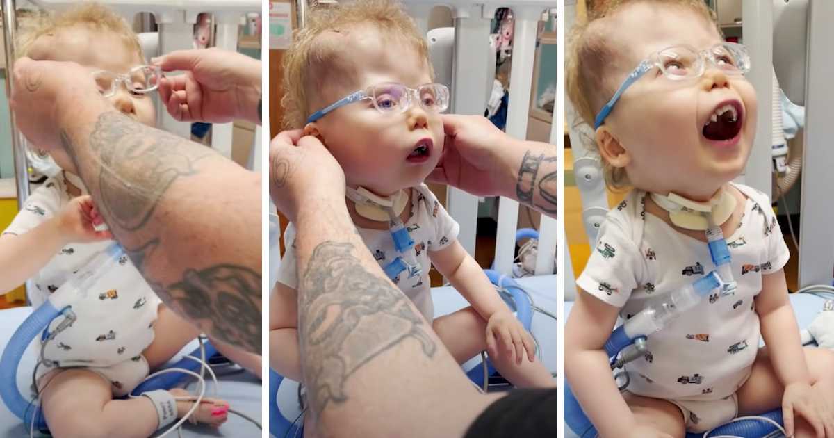 This image shows a sequence of three photos capturing a toddler's heartwarming reaction to wearing new glasses. In the first photo, a parent with tattooed arms is fitting the glasses onto the child, who is seated and connected to medical equipment. The second photo shows the child looking up while wearing the glasses, and in the third, he is beaming with joy, his mouth wide open in a delighted expression. The glasses have light blue frames, and the child is wearing a white onesie with colorful prints.