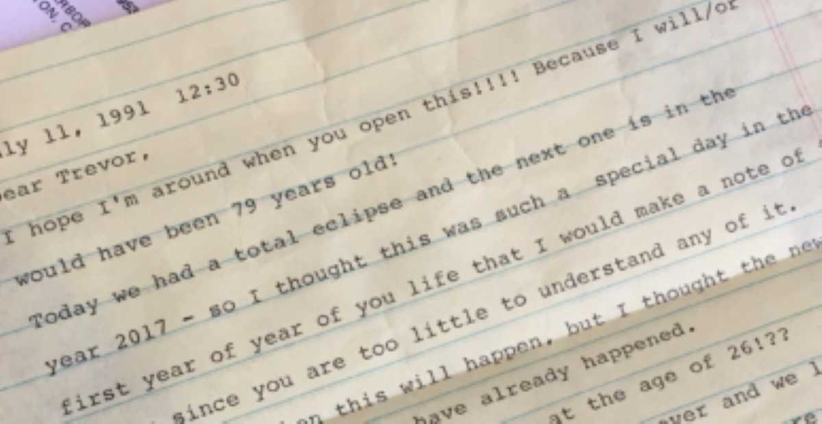 Close-up of a yellowed, typed letter dated July 11, 1991, addressed to a boy named Trevor. The message mentions a total solar eclipse and expresses hope that the writer, Trevor's grandmother, will be alive when he opens the letter in 2017.