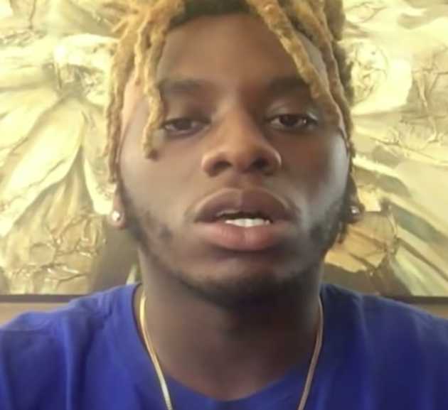 A close-up image of Alonzo Johnson, a young man with light-tipped dreadlocks, wearing a blue shirt and a gold chain, looking into the camera as he speaks.