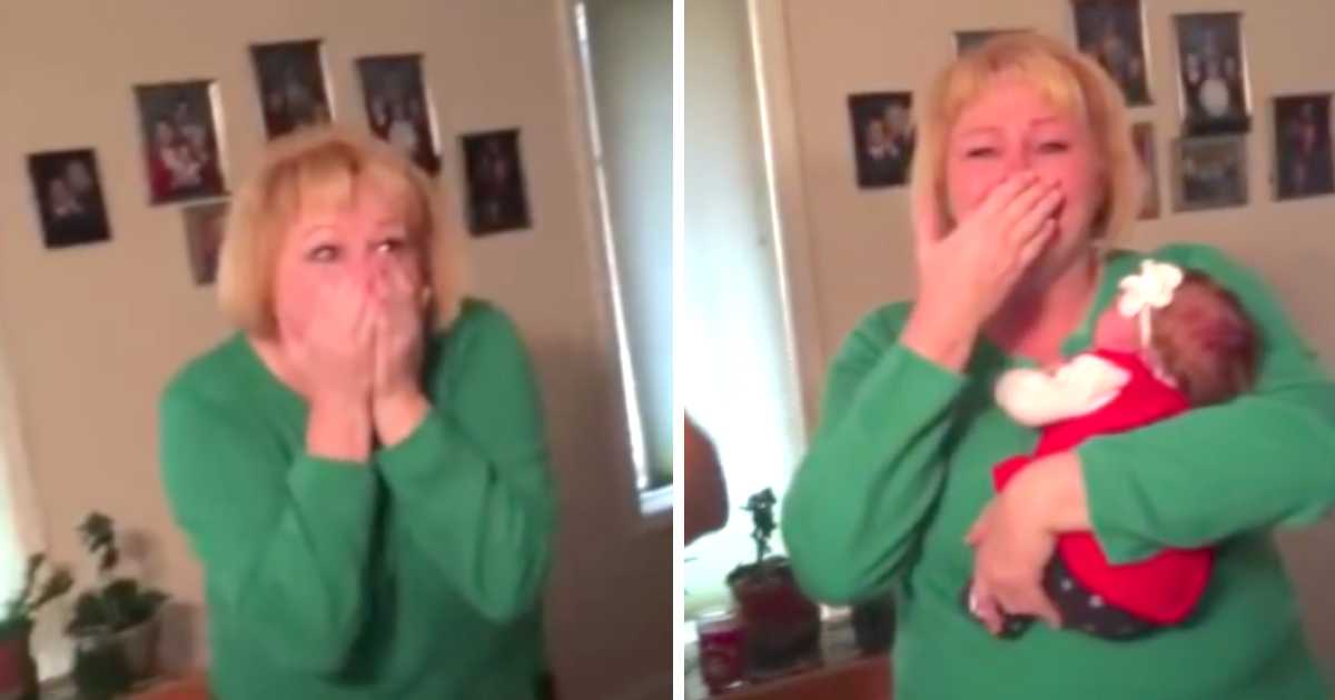 A woman in a green sweater is visibly emotional, covering her mouth in shock and joy. In the first image, she reacts to a surprise; in the second image, she is holding a baby dressed in red with a white bow, still overwhelmed with happiness. Family photos are visible on the wall behind her.