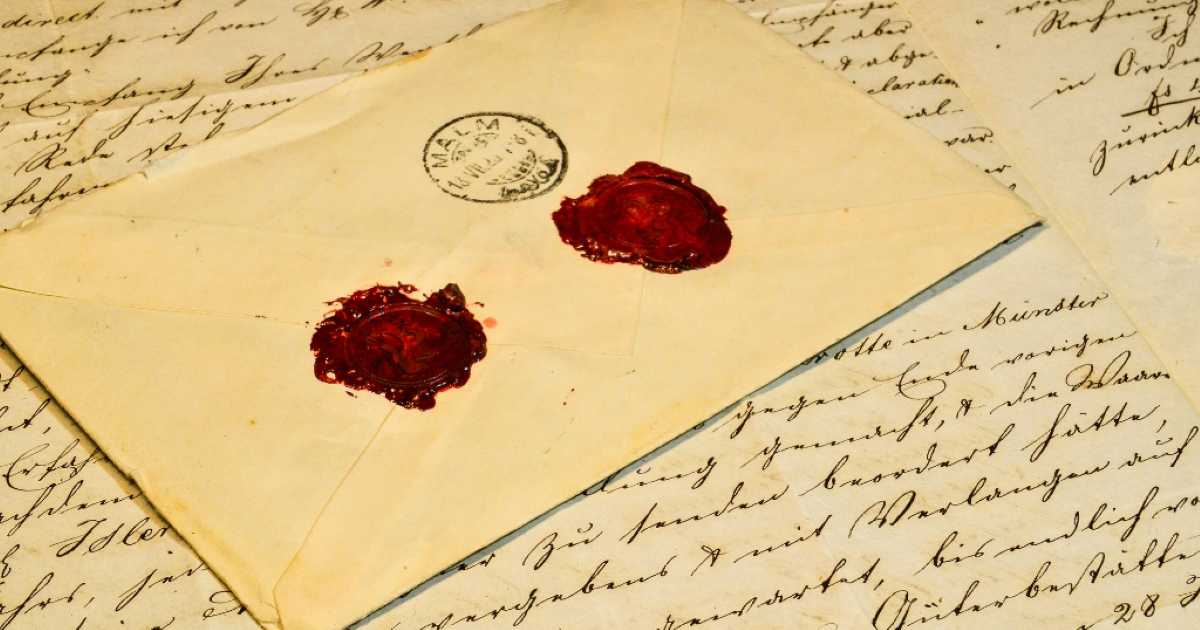 A vintage envelope sealed with two red wax seals rests on top of old handwritten letters, giving a nostalgic and historical feel.