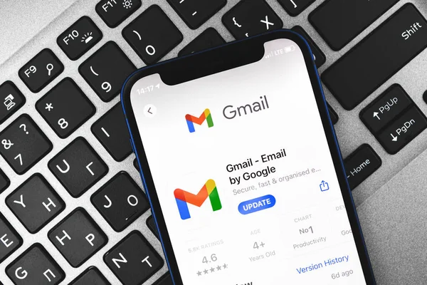 A smartphone showing the Gmail app download screen, resting on a laptop keyboard.