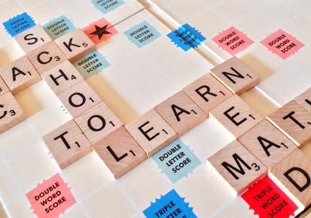 Scrabble board with words like “School,” “Learn,” and “Math” spelled out using wooden letter tiles.