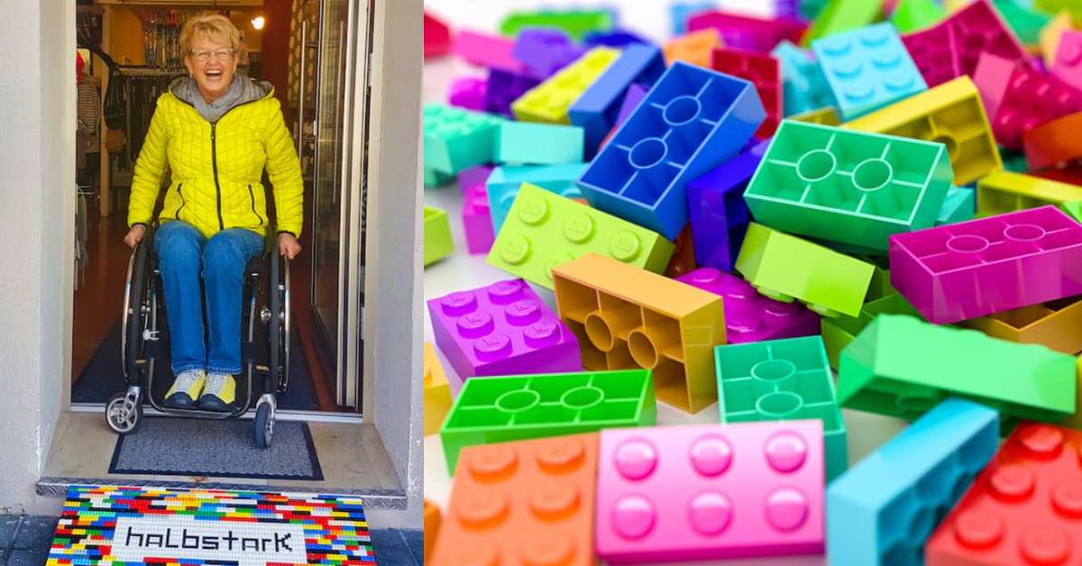 Smiling woman in a wheelchair exits a building using a colorful LEGO ramp; close-up of multicolored plastic LEGO bricks.
