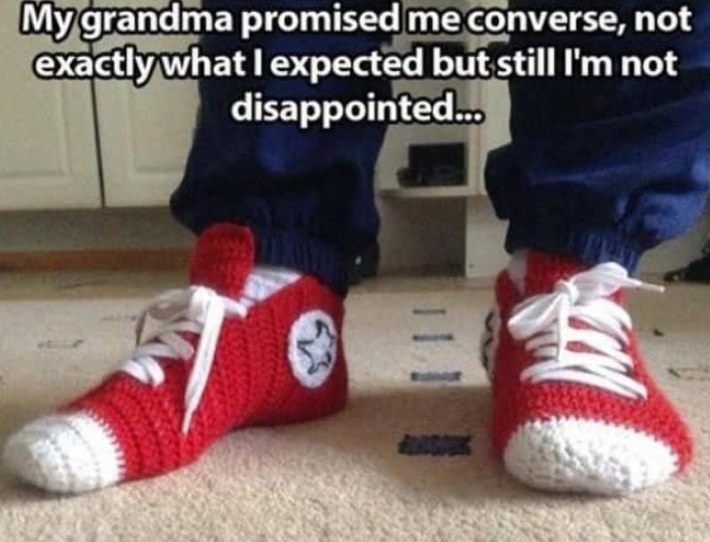Person wearing red crocheted slippers shaped like Converse sneakers with text about grandma’s funny promise.