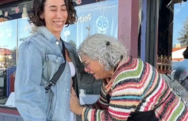 Emotional moment as a smiling daughter embraces her mom, who leans in to touch her growing baby bump.