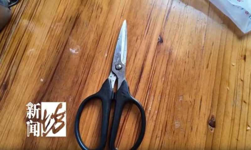 Black-handled kitchen scissors resting on a wooden table.