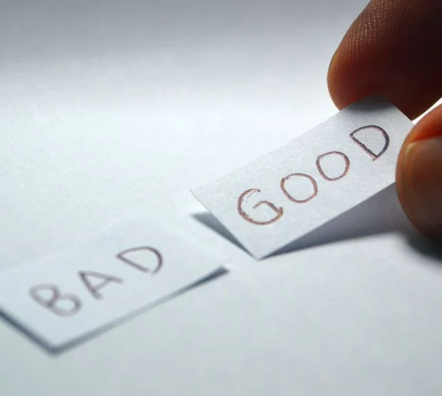 Close-up of a hand choosing a paper slip labeled “GOOD” over another labeled “BAD,” symbolizing decision-making or moral choices.