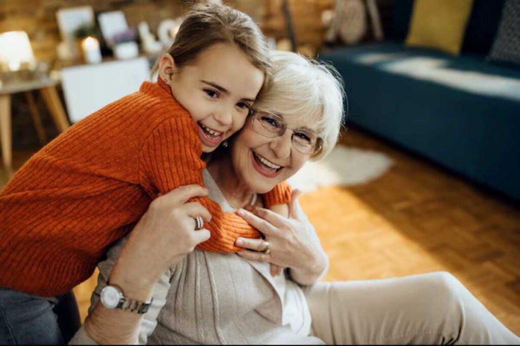 Happy grandmother and young girl share a warm hug and smile together indoors.