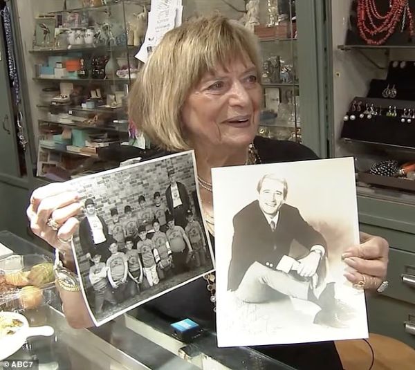 101-year-old woman who still goes to work 6 days a week shares her life advice 3 Elderly woman in a jewelry store holding two black-and-white photos, one of a group of children and another of a seated man.