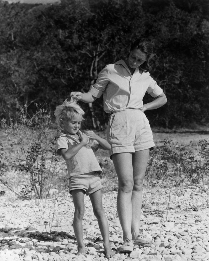 Vintage black-and-white photo of a woman walking outdoors with a young girl holding a nest.