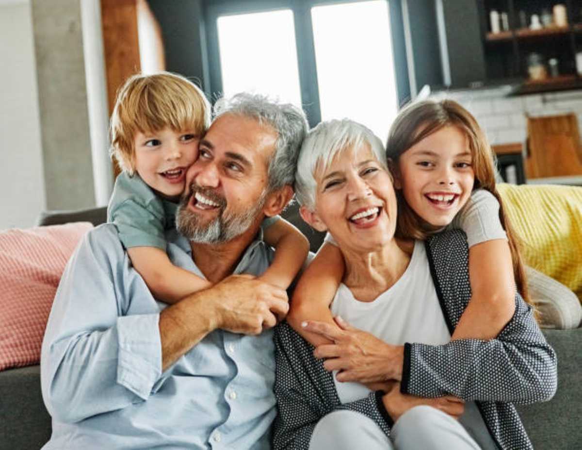 A joyful family of four embracing on a cozy couch, surrounded by warm decor and natural light.