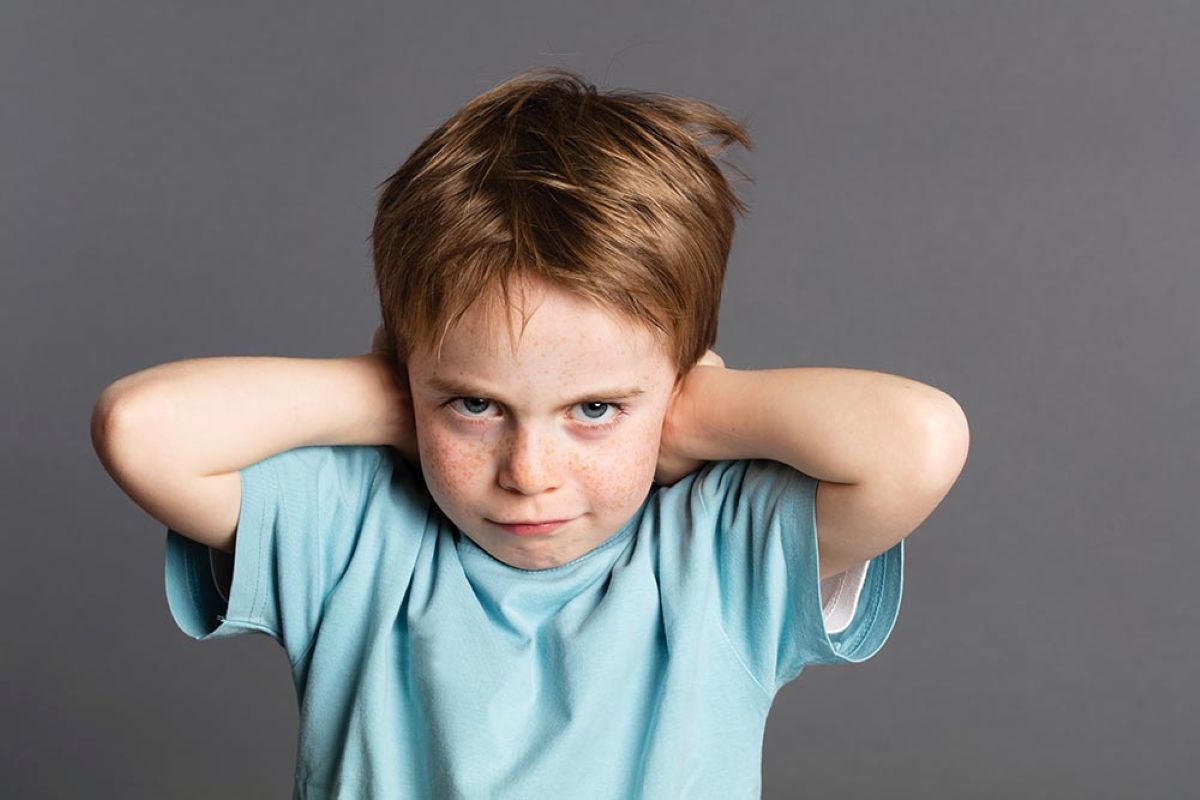 Stubborn young boy closing his ears.