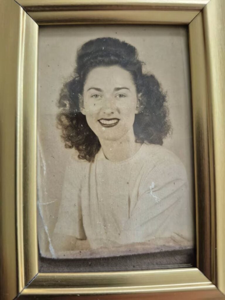 Framed vintage portrait of a smiling young woman with curly hair, wearing a light-colored blouse.