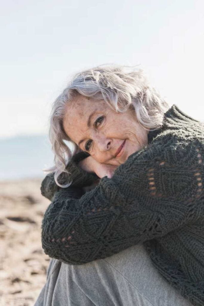 If you don’t want to be miserable for the rest of your life, stop doing these 12 things 3 An elderly woman stands outdoors with a calm, thoughtful expression, natural light highlighting her face and gray hair, conveying quiet confidence, maturity, and peaceful reflection.