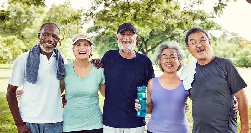 Psychology says people raised in the 1960s and 70s developed these 7 mental strengths that are rare today 5 A diverse group of older adults smiling with their arms around each other during a walk in the park.