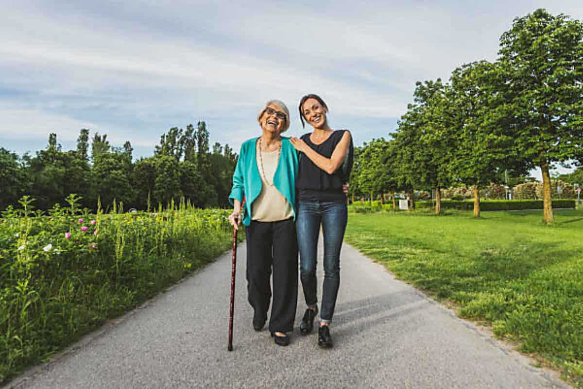 Smiling grandmother and granddaughter walking together on road.