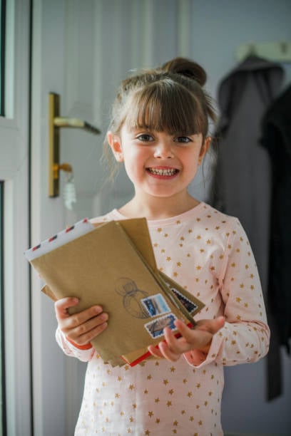 30 Positive Things to Say, Write, Email or Text Your Grandchild From a Distance 3 Smiling young girl standing by the front door, holding a stack of letters and envelopes she received in the mail.