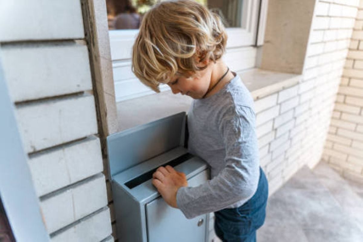 Young boy excitedly checking the mailbox for a letter or surprise delivery.